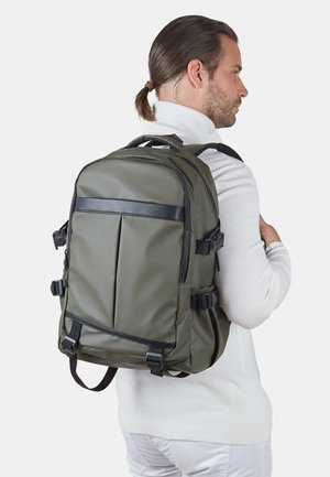 Mochila verde caqui con un diseño estructurado, que presenta una banda de acento negra, correas ajustables y múltiples bolsillos exteriores.