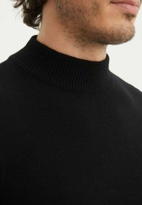 Pull noir à col haut avec des détails côtelés. Texture douce, design ajusté et un matériau de poids moyen, idéal pour être superposé par temps frais.