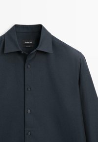 Granatowa koszula na guziki wykonana z gładkiego materiału, z klasycznym kołnierzykiem, sześcioma guzikami oraz metką z napisem "Massimo Dutti."