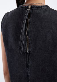 Black denim dress with a back zip closure. Features a clean, minimalist design and subtle texture, emphasizing its casual style.