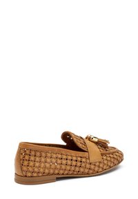 Mocassini intrecciati beige con un pannello in pelle liscia, accessorio in metallo dorato e suola piatta con una superficie texture che mostra motivi intricati.