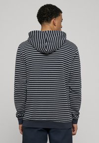 Gestreepte hoodie in marineblauw en wit, voorzien van een capuchon met trekkoord, geribbelde manchetten en zoom, gemaakt van zachte stof met een gestructureerde afwerking.