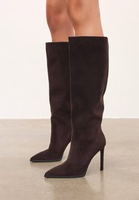 Smeđe antilop čizme do koljena s šiljastim prstom i stiletto petom. Glatka tekstura i elegantan dizajn s prilagođenom siluetom.