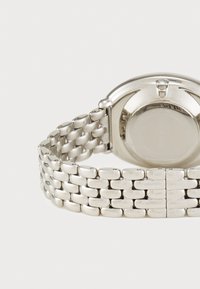 Silver wristwatch with a mesh stainless steel band, round case, smooth surface, and a visible crown, showcasing a polished finish.