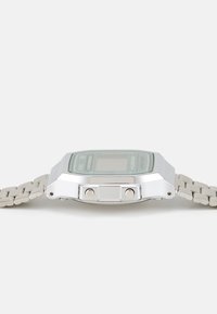 Montre numérique avec un cadran vert, un boîtier en métal argenté et un bracelet gris clair. Dispose de deux boutons sur le côté et d'un design rectangulaire.