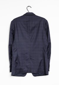 Blazer a quadri blu appeso a un gancio. Caratterizzato da rever a punta, spalle strutturate, due spacchi posteriori e polsini con bottoni.