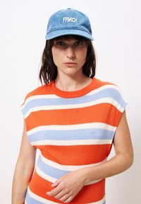 Blauer Samtcap mit in Weiß gesticktem "FRNCH"; orange-blau-creme gestreiftes Strickoberteil mit rundem Halsausschnitt und kurzen Ärmeln.