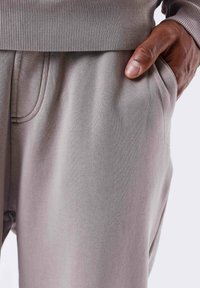 Grijze sweatpants met een zachte textuur, voorzien van zijzakken, een geribde tailleband en zichtbare stikseldetails.