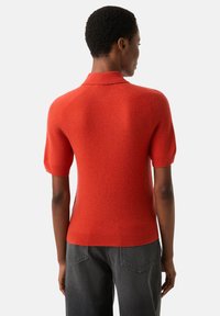 Rotes kurzärmliges Strick-Poloshirt mit strukturierter Oberfläche und geripptem Saum. Verfügt über einen klassischen Kragen und eine schlanke Passform.