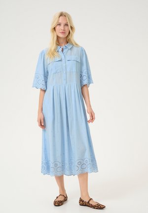 Light blue, button-down dress with short sleeves, embroidered details, and eyelet lace trim at the hem; model wearing leopard print flats.