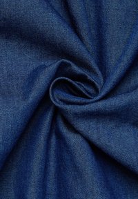 Tessuto in denim blu scuro, finemente lavorato con una superficie liscia e testurizzata, raccolto in una formazione a spirale, che mette in mostra un colore intenso e una delicata lucentezza.