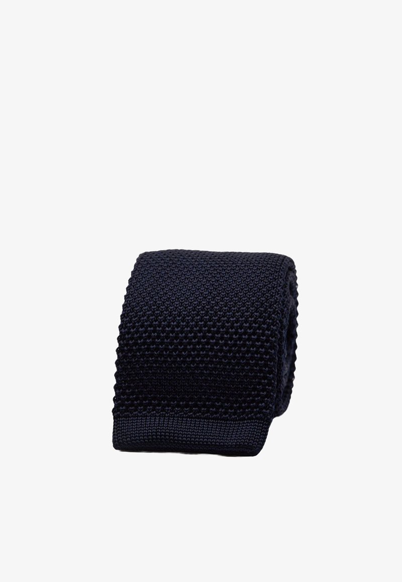 Marineblauwe gebreide stropdas met een gestructureerd patroon en een platte punt. Het materiaal voelt zacht aan met een mix van verhoogde steken. De breedte is ongeveer 6,5 centimeter.