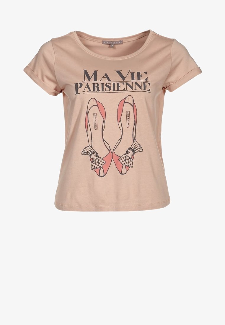 T-shirt en coton rose clair avec des manches courtes, présentant un design imprimé de chaussures roses avec des nœuds à pois noirs et le texte "Ma Vie Parisienne."