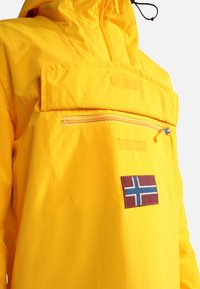 Yellow jacket with a front zipper pocket, Velcro flap, and a Norwegian flag patch on the chest area.