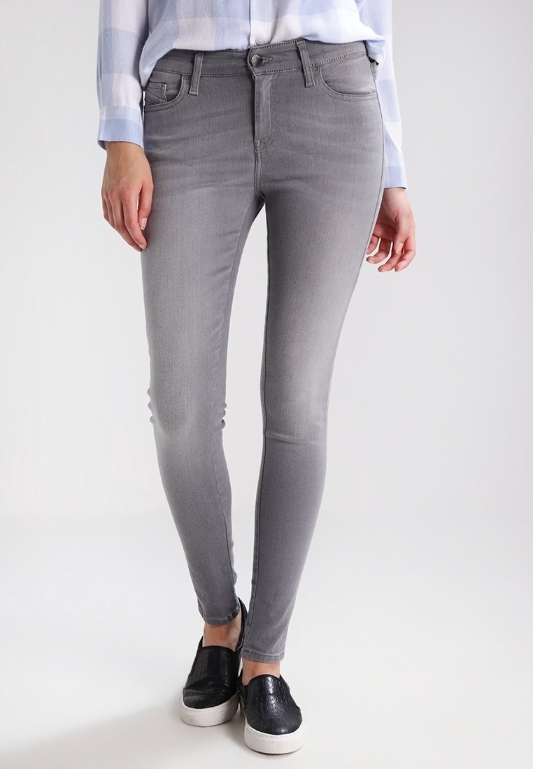 Jeans ajustados de mezclilla gris con cintura media, que presentan una textura suave y un ligero desgaste, combinados con zapatos negros sin cordones.