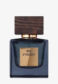 Flacon de parfum en verre de couleur marine foncée, de forme carrée, avec une étiquette dorée portant l'inscription "ROI D'ORIENT", surmonté d'un capuchon en bois texturé.