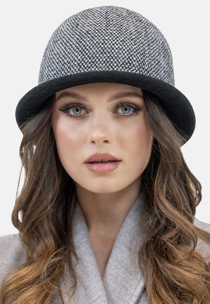 Chapeau cloche gris à motif fabriqué en matériau tissé, avec une large bordure noire. Texture lisse avec une construction de couronne ronde.