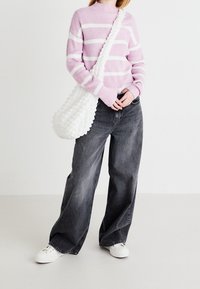 Różowy i biały sweter w paski, szerokie spodnie dżinsowe w ciemnoszarym kolorze, biała torebka na ramię z teksturą oraz białe trampki.