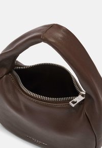 Miękka brązowa skórzana torebka z wypukłym uchwytem, otwartym srebrnym zamkiem błyskawicznym i ciemnym wnętrzem, z subtelnym napisem marki w pobliżu podstawy.