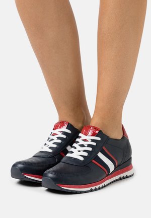 Marineblauwe sneakers met witte en rode strepen. Gemaakt van synthetisch materiaal met mesh accenten. Voorzien van een rubberen zool en witte veters.