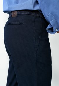 Marineblauwe geruite broek met een geweven zwarte riem met bruine accenten, zijzakken en een gestroomlijnde pasvorm voor comfort.