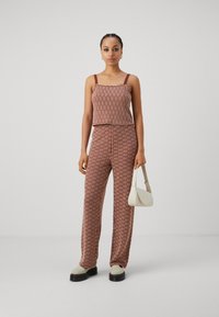 Ensemble tricoté en deux pièces comprenant un haut ajusté et un pantalon large taille haute en rouge et crème avec un motif texturé.