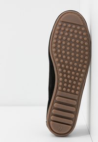 Black suede shoe with a rubber outsole featuring textured grip dots and ridges; size marked as 37. Flat design with smooth edges.