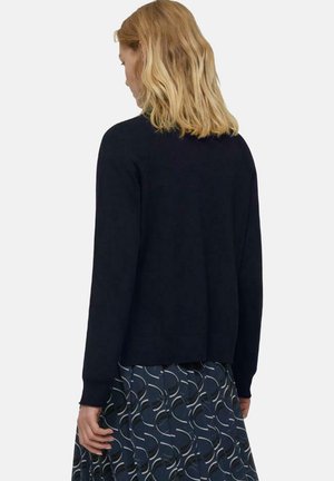 Cardigan a maglia navy con maniche lunghe, scollo rotondo e orlo dritto. Il modello lo indossa sopra una gonna stampata con linee curve.