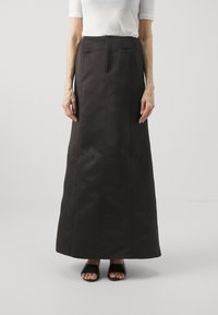 Svart, gulvlång kjol med en strukturerad passform. Har vertikala sömmar och en jämn textur. Matchas med svarta sandaler.