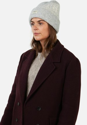 Gorro de canalé gris claro con doblez y parche de logo, combinado con un abrigo burdeos oscuro tipo sastre de doble botonadura y un suéter de punto gris claro.