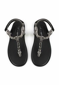 Mustad sandaalid, millel on lame tall, metallist kett ja dekoratiivsed aktsendid rihmadel, pakkudes minimalistlikku disaini.