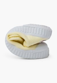 Sneaker bianco con suola in gomma texturizzata, caratterizzato da un interno in morbido cotone giallo. La scarpa è piegata per mostrare il design interno.