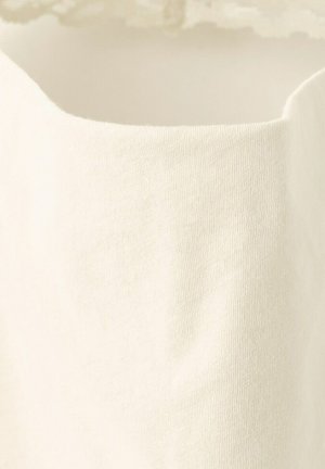 Close-up of a cream-colored, knit fabric with a curved edge and fine ribbed texture.