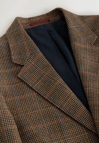 Brown and navy plaid blazer with a houndstooth pattern, featuring a notched collar and black lining on the interior.