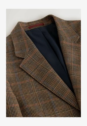 Pruun ja tumesinine ruuduline bleiser, millel on hounds-tooth muster, varustatud lõigatud krae ja musta voodriga seest.