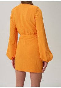 Krátké oranžové šaty s dlouhými nafouklými rukávy a stahováním v pase, s jemnou texturou a hladkým povrchem.
