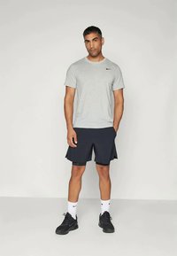 Pelēks īsām piedurknēm Nike T-krekls, tumši zilas šortus, baltas zeķes un melnus kedas. Vienkāršs dizains ar Nike logo uz krekla. Gluda tekstūra.