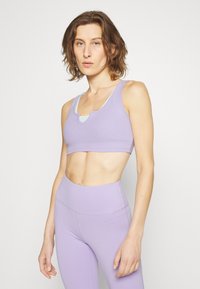 Top desportivo lavanda curto com decote redondo, combinado com leggings lavanda de cintura alta. Textura suave, costuras mínimas e design ajustado.