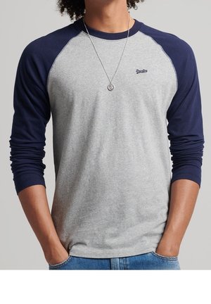 Grijs T-shirt met lange mouwen en marineblauwe raglanmouwen. Voorzien van een ronde hals, een subtiel logo op de borst en een relaxte pasvorm. Gemaakt van een zachte katoenmix.