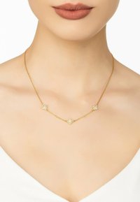 Gold chain necklace featuring three floral shapes adorned with clear stones. The chain has a delicate, twisted texture.