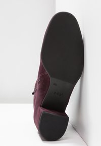 Semelle et talon d'une botte en daim bordeaux avec une semelle en caoutchouc noir texturé, taille 4½, marque Högl visible sur la semelle.