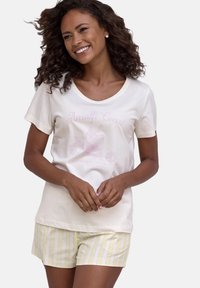 Cremfarbendes T-Shirt mit pinkem Grafiktext "Amalfi Coast" über einer Cocktailillustration, kombiniert mit hellgelben und weißen gestreiften Shorts.