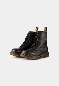 Botas de tobillo de cuero negro con punta redonda, cordones de 8 ojales, costura amarilla y una lengüeta amarilla en el cuello. Suela de goma para mayor durabilidad.