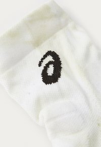 Bijela čarapa sa teksturiranim materijalom; sadrži crni vezeni logotip koji nalikuje broju 6 na strani.