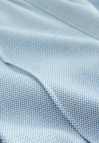 Jasnoniebieska tkanina o małym, kratkowanym wzorze. Gładka faktura z delikatnym połyskiem, złożona w sposób ukazujący głębię i wymiar materiału.