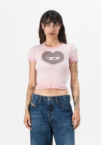 Pink cropped t-shirt with a heart graphic and logo in the center. Short sleeves, ribbed texture, and contrasting stitching detail visible.