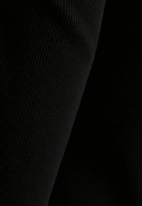 Svart ribbat tyg med en fin textur. Bilden visar flera veck och lager, vilket betonar det mjuka, elastiska materialet.