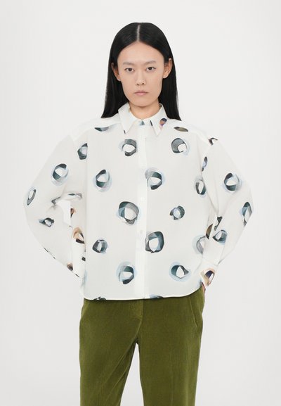 Camisa blanca de botones con patrones circulares abstractos en tonos de azul, negro y marrón; corte relajado con mangas largas.