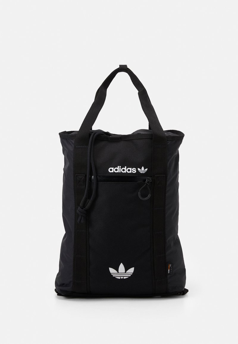 Černá taška Adidas s dvojitými uchy, přední kapsou na zip, bílým potiskem loga a detaily se stahovací šňůrkou na čistém bílém pozadí.