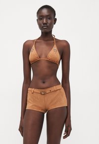 Top bikini in suede color sabbia con coppe triangolari e perline decorative, abbinato a pantaloni corti a vita alta con cintura.